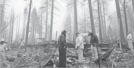  ?? KATHLEEN RONAYNE/AP ?? After a brief delay to let a downpour pass, volunteers resume their search for human remains at a mobile home park in Paradise, Calif., on Friday. Fire officials fear the death toll from the Camp Fire will climb.