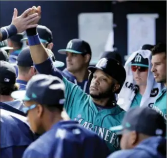  ?? CHARLIE RIEDEL — THE ASSOCIATED PRESS ?? The Mariners’ Robinson Cano celebrates in the dugout after scoring when Tyler O’Neill was walked with the bases loaded during the third inning against the San Diego Padres, Sunday in Peoria, Ariz.