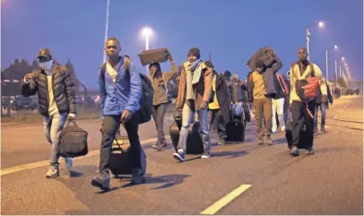  ?? THIBAULT CAMUS, AP ?? Migrants carrying their belongings leave a makeshift camp known as “The Jungle” near Calais, northern France, to register at a processing center Monday. French authoritie­s say the closure of the slum-like camp will last about a week.