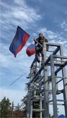  ?? ?? Een Oekraïense soldaat verwijdert de vlag van de zelfverkla­arde republiek