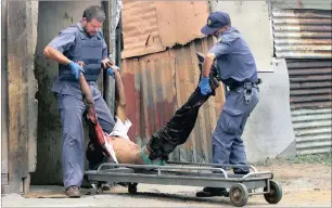  ??  ?? POLITICAL UNREST: South African police carry the body of a man who was shot dead by unknown gunmen at the Mandela squatter camp in Katlehong, Ekurhuleni, during the local government elections on December 5, 2000.