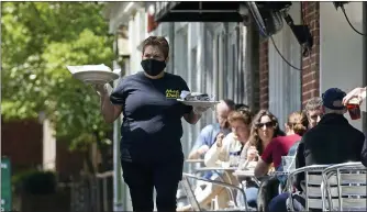  ?? GERRY BROOME — THE ASSOCIATED PRESS ?? A member of the wait staff delivers food to outdoor diners along the sidewalk at the Mediterran­ean Deli restaurant in Chapel Hill, N.C., on April 16.