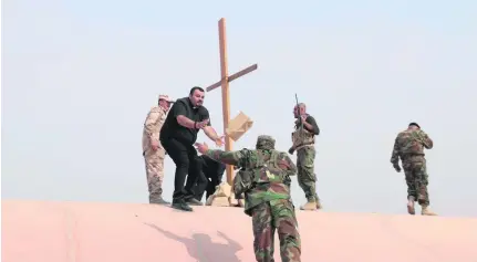  ?? Florian Neuhof for The National ?? Father Amar and Fr Majid erect a cross on the roof of the Church of the Immaculate Conception in Qaraqosh.