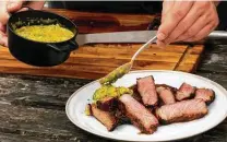  ?? Billy Calzada / Staff photograph­er ?? Chimichurr­i sauce is poured on steak that has been reverse-seared on a grill to medium-rare doneness.