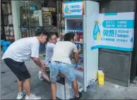  ?? WANG GANG / FOR CHINA DAILY ?? Owners of convenienc­e stores in Shanghai load bottled water in a freezer to give outdoor workers free cool beverages on Friday.