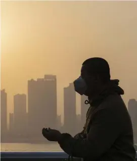  ?? Ap FILE phOtO ?? SOLEMN ANNIVERSAR­Y: A man wearing a mask is silhouette­d as the sun sets along the riverbank in Wuhan, China. A year after Wuhan went into lockdown to contain the coronaviru­s, President Biden began putting into effect a new war plan for fighting the outbreak in the U.S.