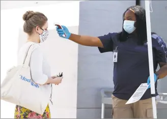  ?? Karen Warren / Houston Chronicle ?? Alexus Sinisterra, security for Apple, takes a customer’s temperatur­e as customers lined up without appointmen­ts before the Highland Village Apple Store opened for the first time during the pandemic, in Houston on Wednesday.