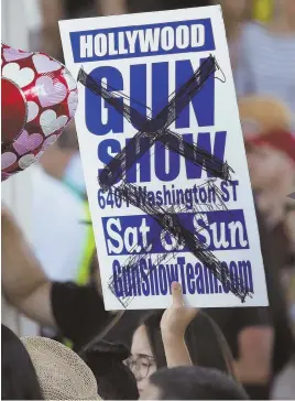  ?? AP PHOTO ?? SHOW OF DEFIANCE: A protester holds up a defaced poster for a gun show at yesterday’s rally in Fort Lauderdale, Fla.