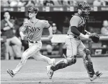  ?? Steve Nesius / Associated Press ?? Joey Wendle darts past Astros catcher Max Stassi to put the Rays up 2-1 on Matt Duffy’s two-run single in the seventh.