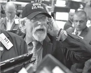  ??  ?? Trader Peter Tuchman wears a ‘Dow 22,000’ hat as he works Wednesday on the floor of the New York Stock Exchange. A big gain for Apple sent the Dow Jones industrial average above 22,000 for the first time.