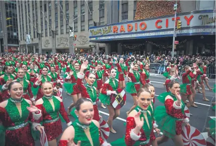  ?? Eduardo Munoz Alvarez, The Associated Press (above); Calla Kessler, © The New York Times Co. (below) ?? Participan­ts in the Macy’s Thanksgivi­ng Day parade — the Spirit of America dancers, above, and the Olaf balloon, below — make their way down Sixth Avenue in New York on Thursday.