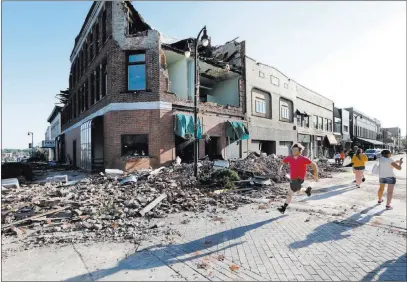  ?? Charlie Neibergall ?? The Associated Press A resident runs past a tornado-damaged building Thursday on Main Street in Marshallto­wn, Iowa. Several buildings were damaged by a tornado in the main business district, including the historic courthouse.
