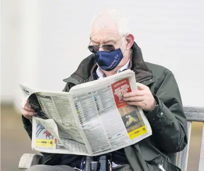  ??  ?? A racegoer checks the form at Cheltenham on Friday