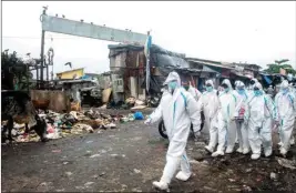  ??  ?? Health workers wearing PPE kits arrive to conduct medical checkup of the residents in a COVID-19 containmen­t zone at Malad in Mumbai, on Monday