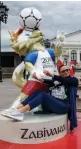  ??  ?? A woman poses with a statue of the World Cup mascot Zabivaka in Moscow.