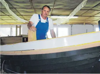  ??  ?? Bootsbauer Ralf Asmus (li.) repariert auch traditione­lle Fischkutte­r in Holzbauwei­se, Jonas Renken ist Segelprofi – und hat in der Werkstatt am Hafen von Warnemünde jede Menge zu tun.
