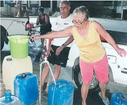  ??  ?? Una abonada de Asry llena tambos con agua en una estación gasolinera ante la falta del recurso en su hogar.