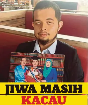  ??  ?? AFIQ menunjukka­n gambar kenangan bersama ibunya pada majlis konvonya yang lalu.