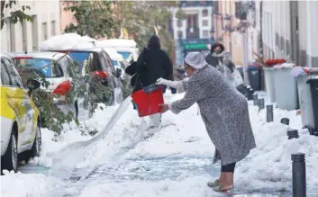  ?? — Reuters ?? A woman throws water on a snow-covered street, following heavy snowfall in Madrid.