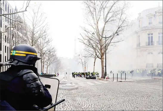  ??  ?? Protestors wearing ‘yellow vests’ (gilets jaunes) demonstrat­e amid smoke during a protest against rising oil prices and living costs, near the Champs Elysees Avenue in Paris, on Dec 8. (AFP)