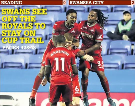  ??  ?? > Alfie Mawson is mobbed after putting Swansea ahead at the Majdeski Stadium last night