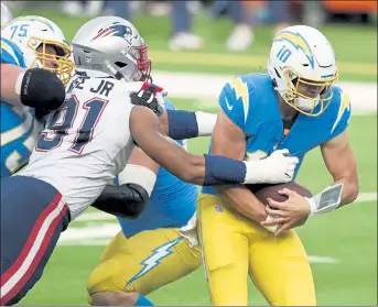  ?? AP ?? Chargers quarterbac­k Justin Herbert is sacked by Patriots defensive tackle Deatrich Wise during the first half on Sunday.