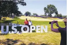  ?? CHARLES KRUPA AP ?? Fans pose at U.S. Open sign during a practice round ahead of the U.S. Open, which starts today at The Country Club in Brookline, Mass.