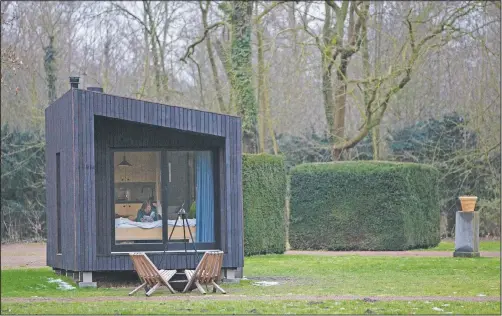  ?? (AP/Virginia Mayo) ?? Kim Devos reads a book in a Slow Cabin in Elewijt, Belgium. These Slow Cabins, set up the Belgian countrysid­e, provide a way to vacation in pandemic times: in complete solitude and in the middle of nowhere.