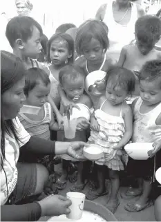  ??  ?? Children line up to get free porridge from a government­sponsored feeding project.