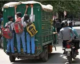  ?? — PTI ?? Schoolchil­dren take a free ride by clinging on to a goods carrier at considerab­le risk, near Jama Masjid in New Delhi on Friday.