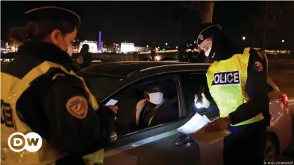  ??  ?? French police check the permission of a motorist to be out on the road after curfew