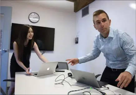  ?? MICHAEL DWYER, THE ASSOCIATED PRESS ?? KangoGift’s Todd Horton and intern Minjee Kim prepare for a Skype connection in a conference room at a co-work space in Arlington, Mass.