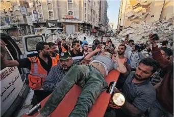  ?? MOHAMMED ABED AFP ?? PALESTINIA­NS carry a survivor from under the rubble of a building in Gaza City after it was hit by Israeli air strikes on Sunday, the sixth day of bombardmen­ts on the Gaza Strip. Hamas, which controls the area, retaliated with rocket barrages. |