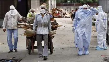  ?? — AP ?? A file photo of workers bringing wood for the funerals of COVID-19 victims at a crematoriu­m