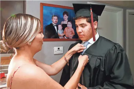  ?? ROB SCHUMACHER/THE REPUBLIC ?? Laura Romo’s son Marco Coss graduated from high school Thursday. His father, Marco Tulio Coss-Ponce (in background photo), was deported earlier this month.