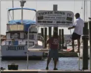  ?? JOHN FITZHUGH — THE SUN HERALD VIA AP ?? Bobby Williams, left, and his son, Bobby, Jr., take down the sign for their charter boat at the Biloxi, Miss., Small Craft Harbor on Friday. Gulf Coast residents were bracing Friday for a fast-moving blast of wind, heavy rain and rising water as...