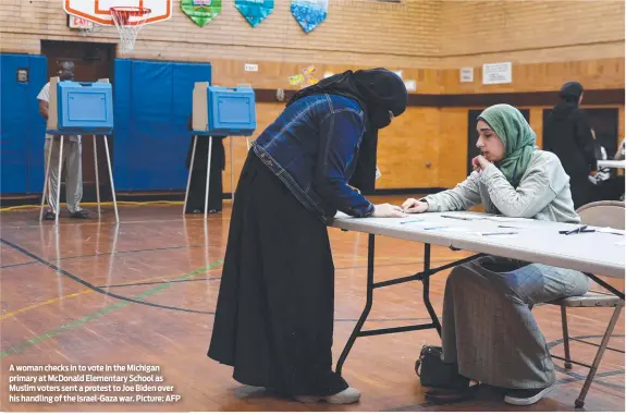  ?? ?? A woman checks in to vote in the Michigan primary at McDonald Elementary School as Muslim voters sent a protest to Joe Biden over his handling of the Israel-Gaza war. Picture: AFP