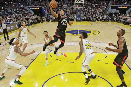  ??  ?? Norman Powell (centre) of Toronto Raptors shoots against the Golden State Warriors during their NBA game in San Francisco on Thursday. The Toronto Raptors carved out a 121-113 victory. —
AP