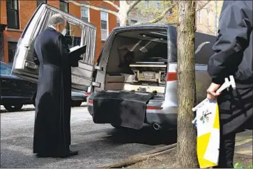  ?? Jessie Wardarski Associated Press ?? MSGR. Kieran Harrington prays for the Rev. Jorge Ortiz-Garay, 49, in Brooklyn, N.Y., before his body is taken to the airport this month. Ortiz-Garay is the first Catholic cleric in the U.S. known to have died of COVID-19.