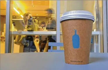  ?? ERIC RISBERG / AP ?? A Blue Bottle Coffee paper to-go cup rests on a table outside one of their cafés in San Francisco. The Oakland-based chain says it’s getting rid of disposable cups at two locations next year, as part of a pledge to go “zero-waste” at its 70 U.S. locations by the end of 2020.