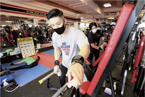  ?? The Yomiuri Shimbun ?? A man disinfects training equipment with alcohol-infused paper towels at a gym in Kita Ward, Osaka, on June 1.