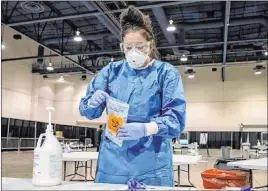  ?? Elizabeth Brumley Las Vegas Review-journal ?? UMC respirator­y therapist Diana Vega seals a COVID-19 test in a biohazard bag at Cashman Center. Nevada’s 602 new cases reported Thursday were below average.