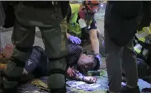  ?? Associated Press ?? Medical volunteers help an injured man after he was attacked by pro-democracy protesters Monday.