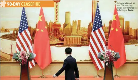  ?? — Reuters ?? A man walks past US and Chinese flags inside a conference hall in Beijing.