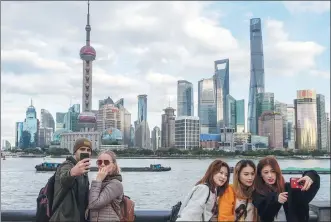  ?? WANG GANG / FOR CHINA DAILY ?? Tourists pose for photograph­s at the Bund, a major scenic spot on the Huangpu River, in Shanghai earlier this month.