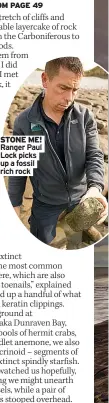  ?? ?? Ranger Paul Lock picks up a fossil rich rock
