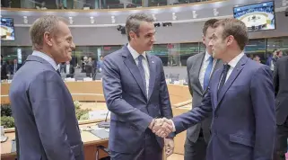  ??  ?? Greek Prime Minister Kyriakos Mitsotakis (center) shakes hands with French President Emmanuel Macron as European Council President Donald Tusk looks on in Brussels yesterday. Mitsotakis warned of rising migratory flows toward Europe.