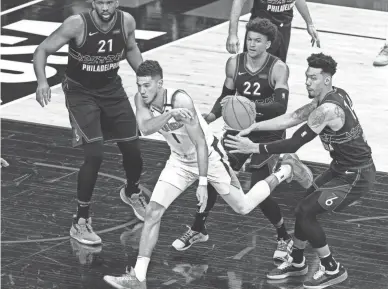  ??  ?? Suns guard Devin Booker passes while defended by 76ers forward Danny Green (14) and guard Matisse Thybulle (22) during the first quarter at Wells Fargo Center in Philadelph­ia on Wednesday.