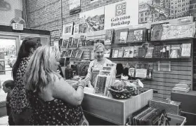  ?? Marie D. De Jesús / Staff photograph­er ?? Galveston Bookshop manager Kimberly Hall talks to customers Emily McMullen and Chris Grim while they pay for books during their vacation last week. The mother and daughter travel to the area from Colorado every year to visit family, and the bookshop is always one of their most important stops.