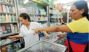  ??  ?? A Venezuelan woman buys items from a pharmacy in neighbouri­ng Colombia. A dire economic crisis has seen thousands of Venezuelan­s cross the border each day to buy food, medicine and other desperatel­y needed supplies.